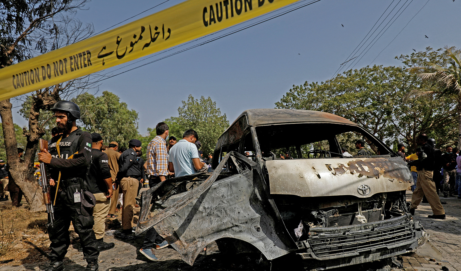 Police officers and crime scene unit gather near a passenger van, after a blast at the entrance of the Confucius Institute University of Karachi, Pakistan April 26, 2022. (REUTERS)