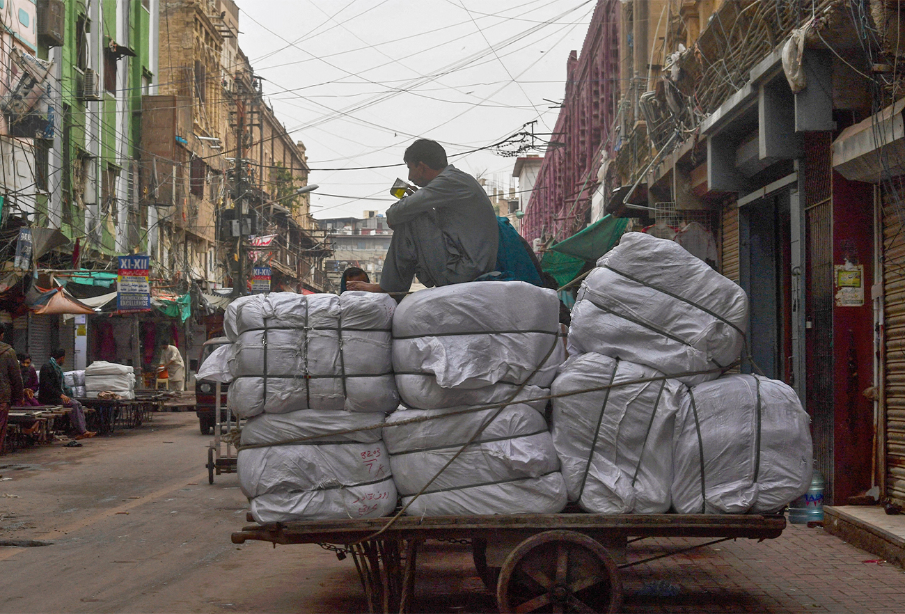 A labourer drinks tea over a loaded cart at a market area in Karachi, Pakistan, on January 6, 2022. (AFP/File)