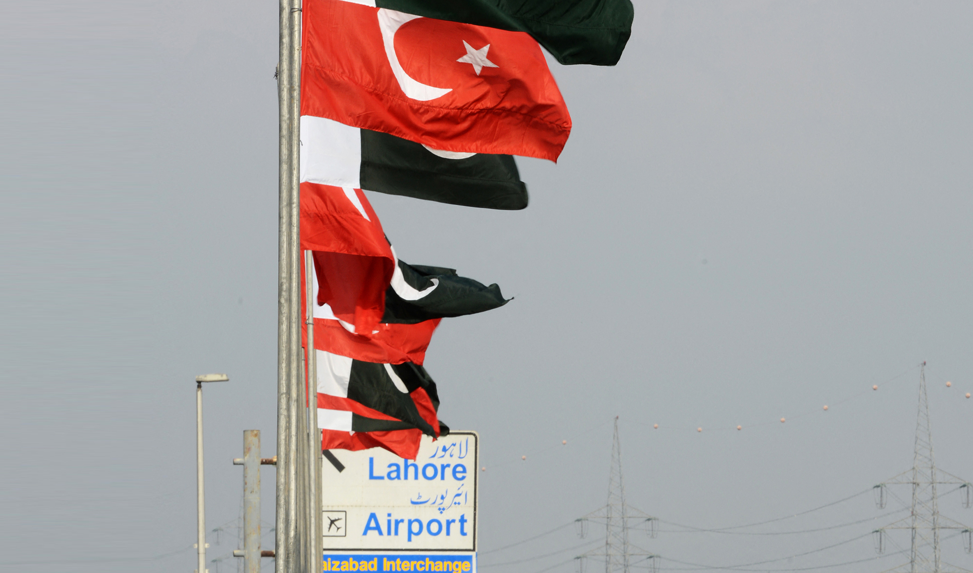 Pakistani commuters stand under the national flags of Turkey and Pakistan on a bridge in Islamabad on December 22, 2013. (AFP/File)