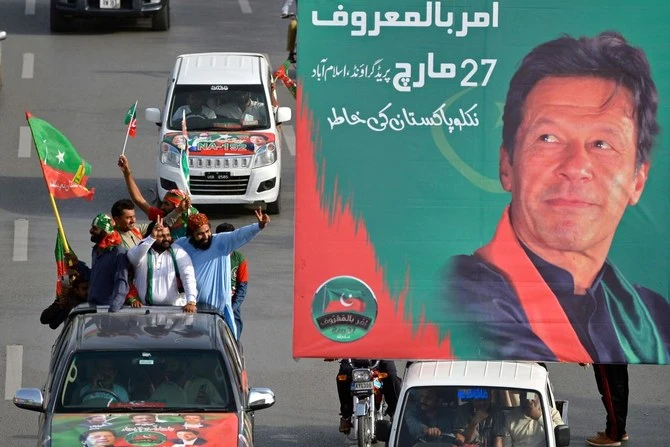 Supporters of the ruling Pakistan Tehreek-e-Insaf party arrive to attend a rally next to a billboard with a picture of Prime Minister Imran Khan in Islamabad on March 27, 2022. (AFP/File)