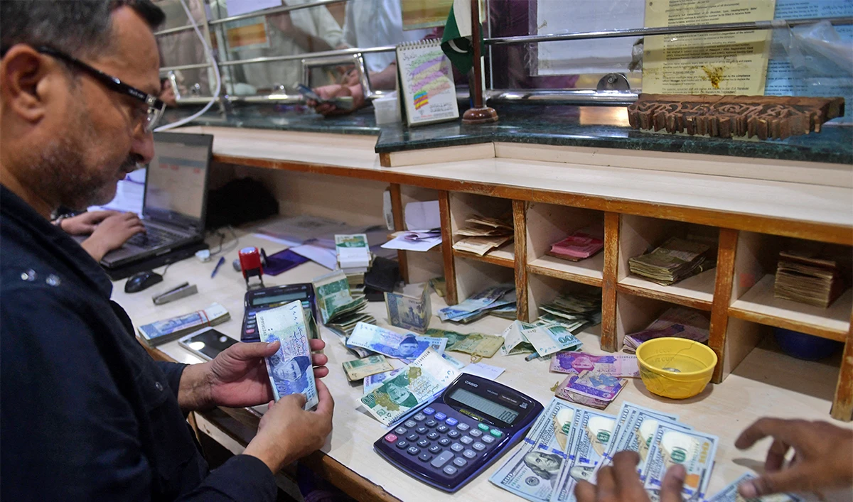 People exchange foreign currency at a shop in Karachi on April 7, 2022. (AFP/File)