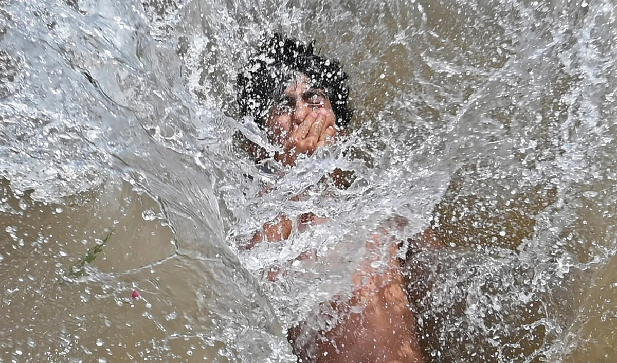 A youth cools himself in a canal during a hot summer day in Lahore, Pakistan, on April 28, 2022. (AFP)