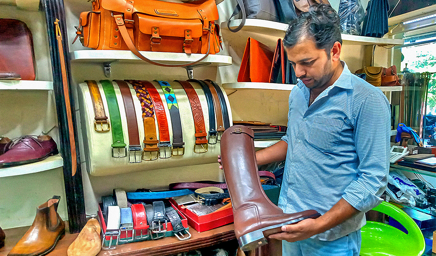 Amjad Rehman holds up a handmade leather boot at his shop in Islamabad, Pakistan, on April 27, 2022. (AN photo)