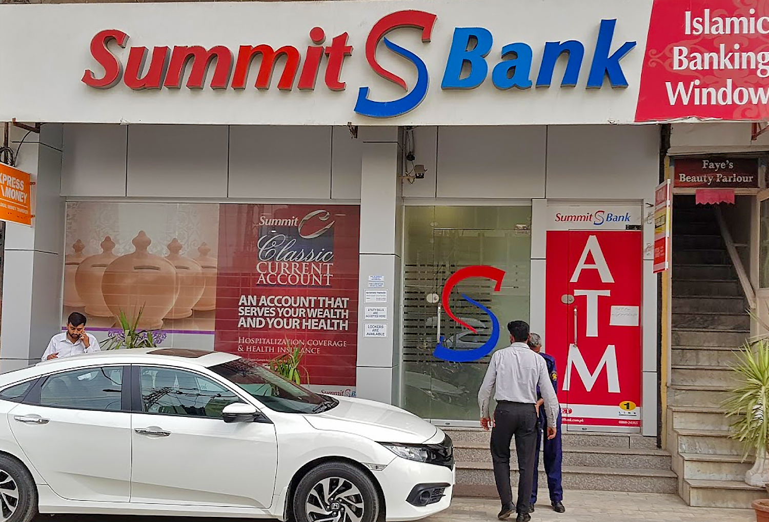 A guard checks the pockets of a customer outside Summit Bank in Rawalpindi, Pakistan, in March 2018. (Photo courtesy: Sohaib Liaquat/Online)