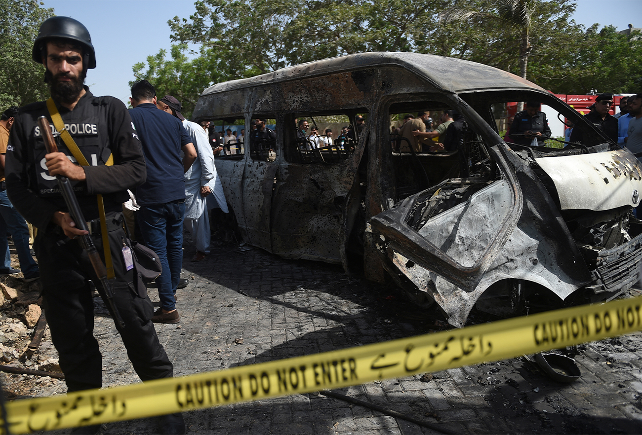 Police inspect a site around damaged vehicles following a suicide bombing in Karachi, Pakistan, on April 26, 2022. (AFP)