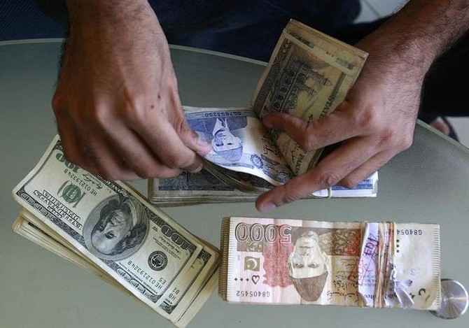 In this file photo, a currency dealer counts Pakistani rupees and U.S. dollars at his shop in Karachi October 8, 2008. (REUTERS/FILE)