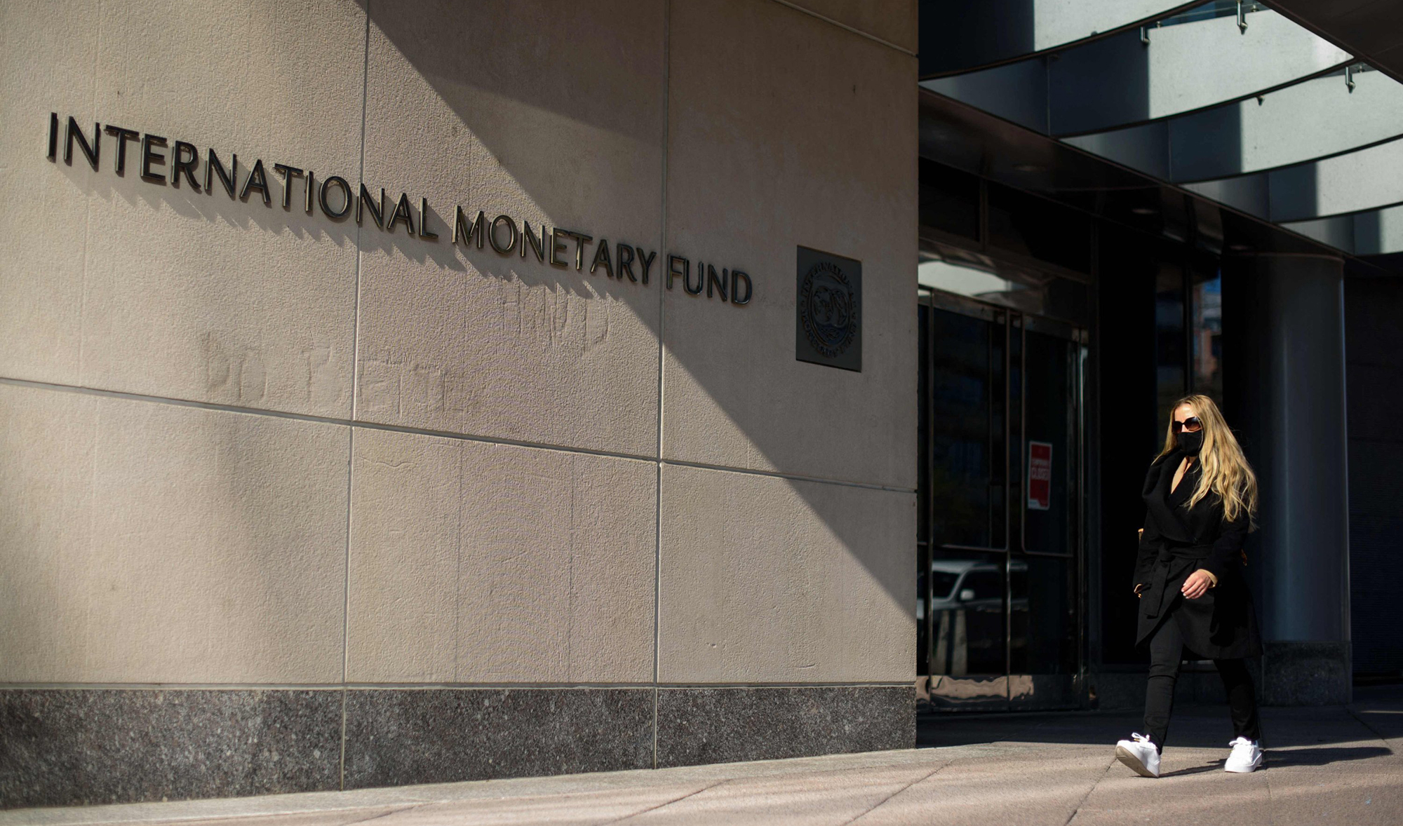 A woman walks past an International Monetary Fund headquarters(IMF) building in Washington, DC on April 5, 2021. (AFP)