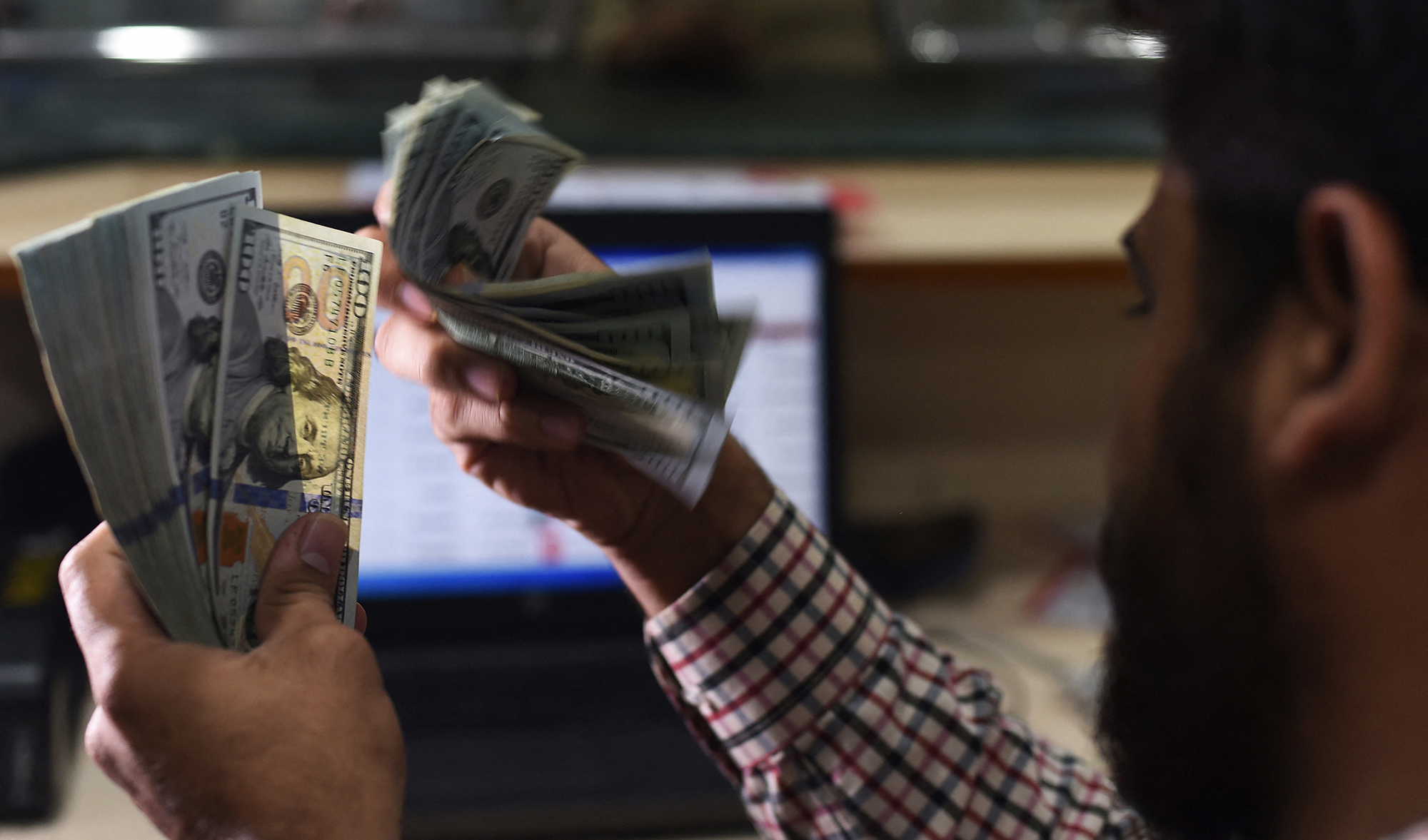 A Pakistani dealer counts US dollars at a currency exchange shop in Karachi on October 9, 2018. (AFP/File)