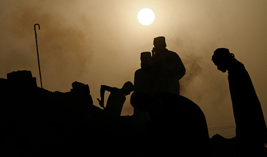 In this picture taken on May 12, 2022, labourers are silhouetted against the sun as they work at a brick kiln factory on a hot summer day during a heatwave in Jacobabad, in southern Sindh province. (AFP)