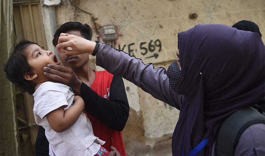 A health worker administers polio vaccine drops to a child during a door-to-door polio vaccination campaign in Karachi on February 28, 2022.(AFP)
