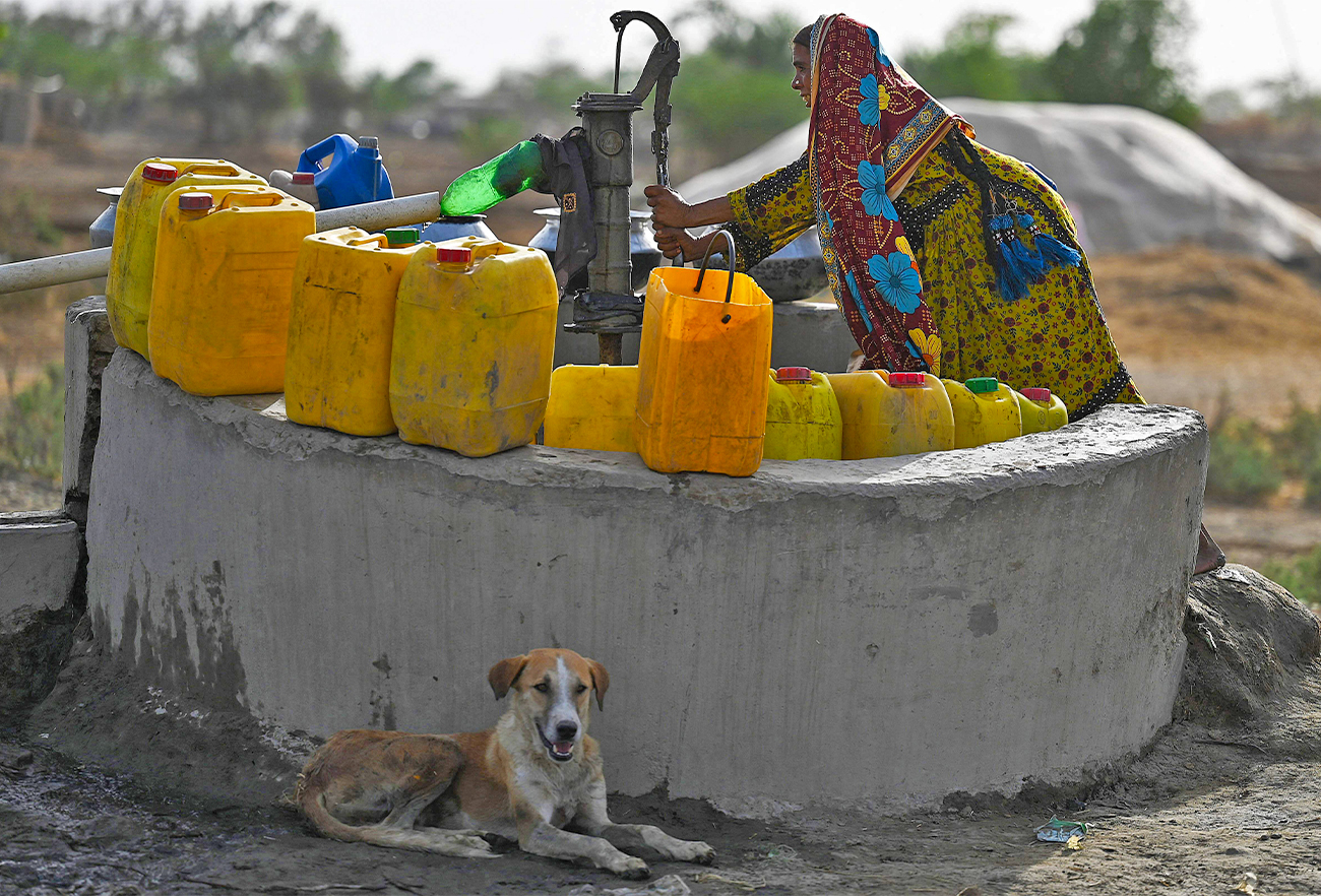 In this picture taken on May 11, 2022, a woman fills containers with water from a hand pump during a heatwave in Jacobabad, in the southern Sindh province. (AFP)