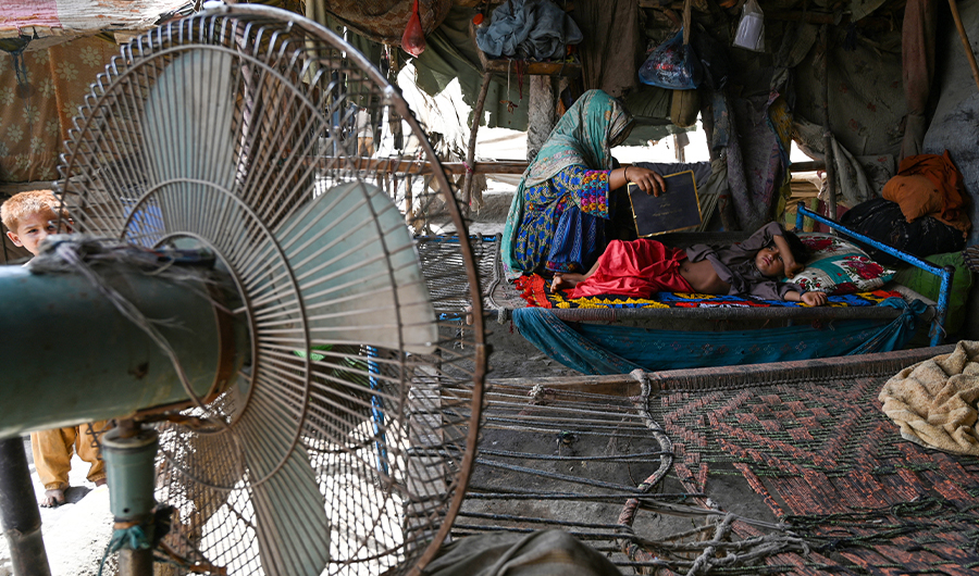 In this picture taken on May 11, 2022, a woman uses a paper sheet to fan her child amid a power cut during a heatwave in Jacobabad, in the southern Sindh province. (AFP)