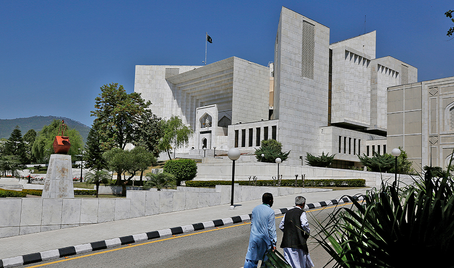 People walks past the Supreme Court where a petition hearing to dissolve parliament by country's Prime Minister is taking place in Islamabad, Pakistan, on April 4, 2022. (AP/File)