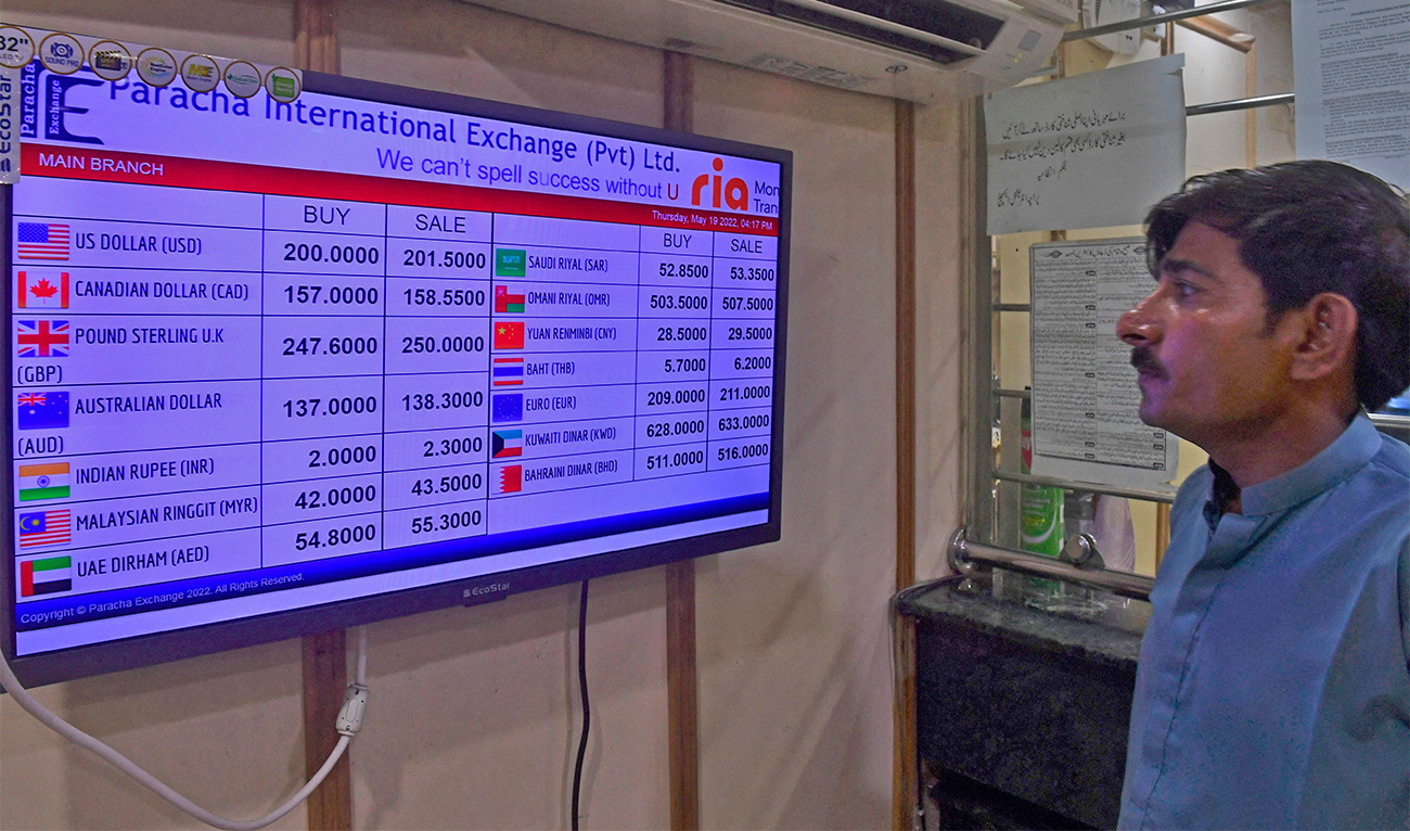 A customer looks at the foreign currency rates displaying at a shop in Karachi, Pakistan, on May 19, 2022. (AFP)