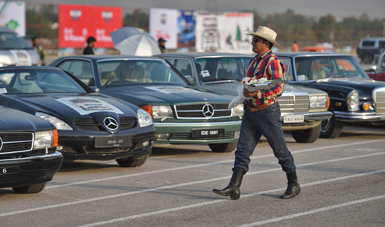 A Pakistani participant walks past vintage cars at the end of the Pakistan Motor Rally in Islamabad on October 23, 2017. (AFP)