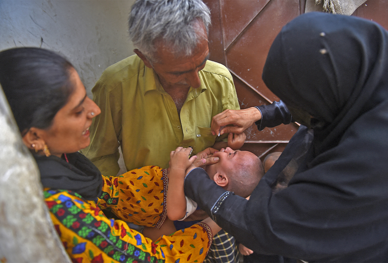 A health worker administers polio vaccine drops to a child during a door-to-door polio vaccination campaign at a slum area in Karachi on May 23, 2022. (AFP/File)