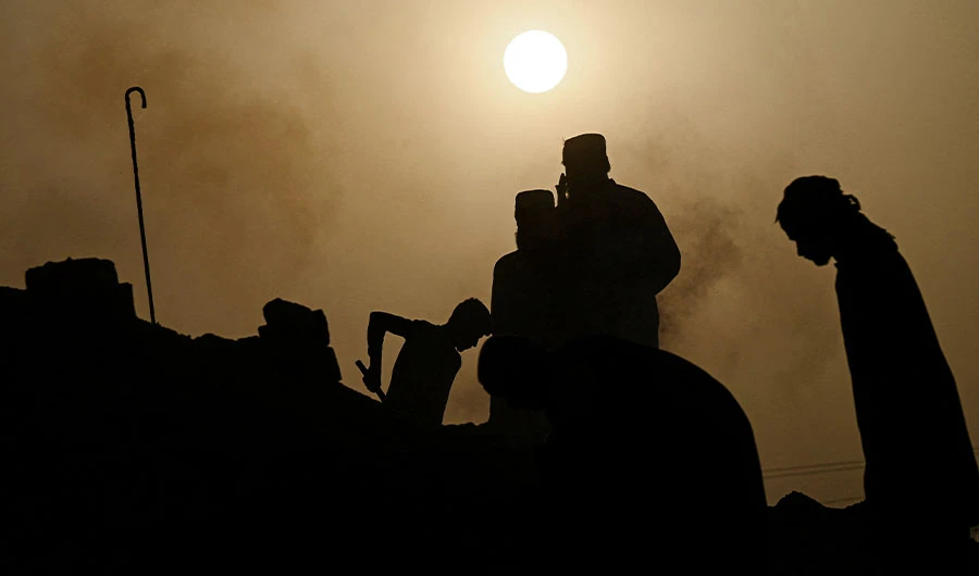 In this picture taken on May 12, 2022, labourers are silhouetted against the sun as they work at a brick kiln factory on a hot summer day during a heatwave in Jacobabad, in southern Sindh province. (AFP)