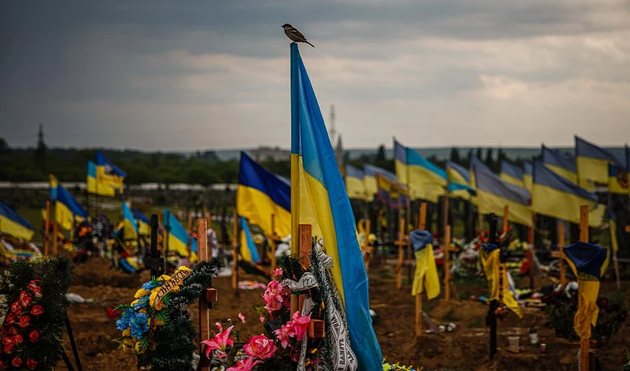 A photo taken on May 21, 2022 shows a bird alights on a Ukrainian flag in the military section of the Kharkiv cemetery number 18 in in Bezlioudivka, eastern Ukraine. (AFP)