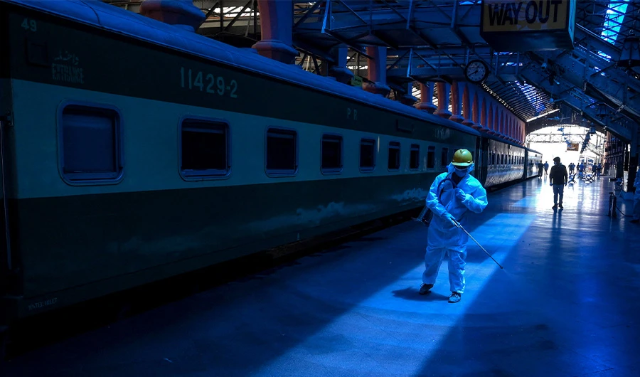 A worker wearing protective gear sprays disinfectant at the railway station in Lahore on May 7, 2020. (AFP/FILE)
