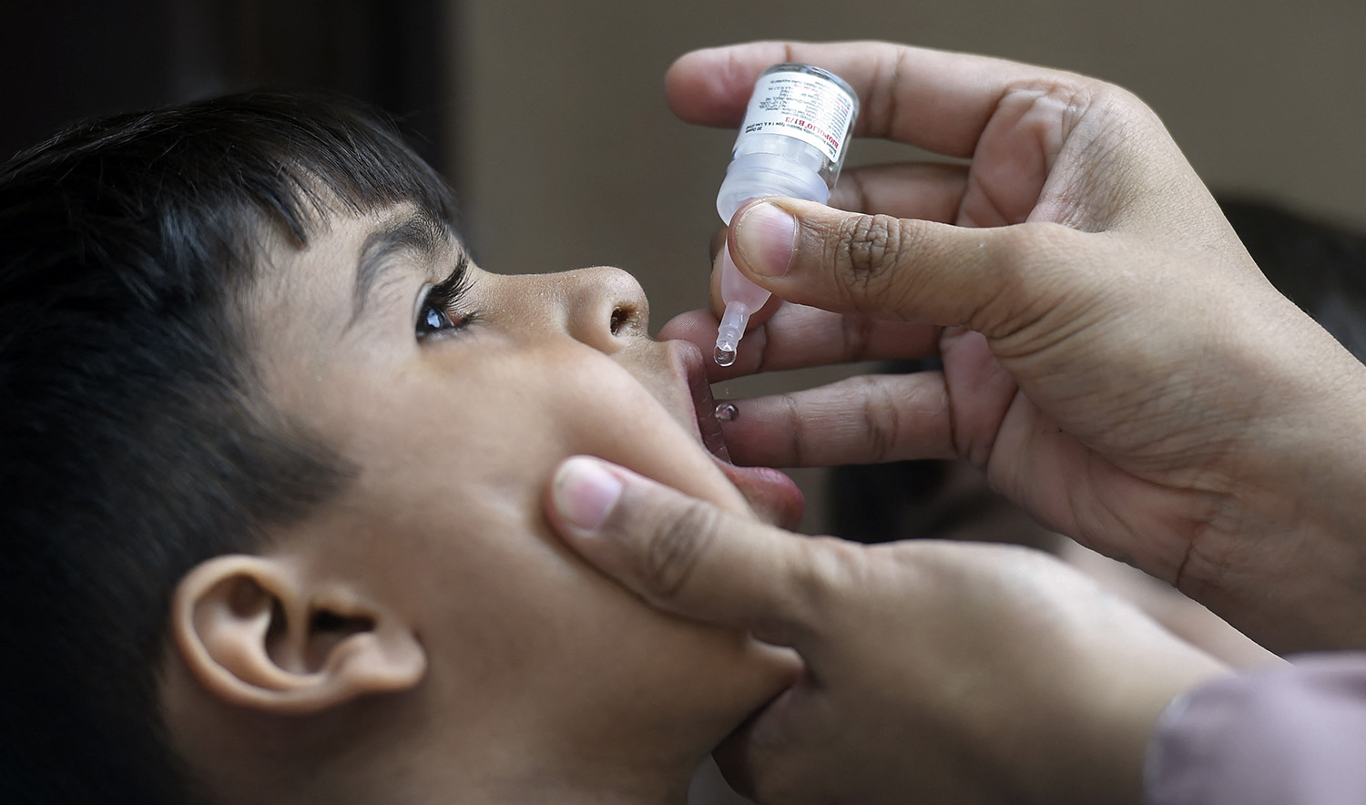 A health worker administers polio vaccine drops to a child during a door-to-door polio vaccination campaign at a slum area in Karachi on May 23, 2022. (AFP/File)