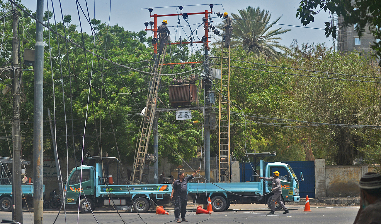 Men work on electric pylons along the roadside in Karachi on May 30, 2021. (AFP/File)
