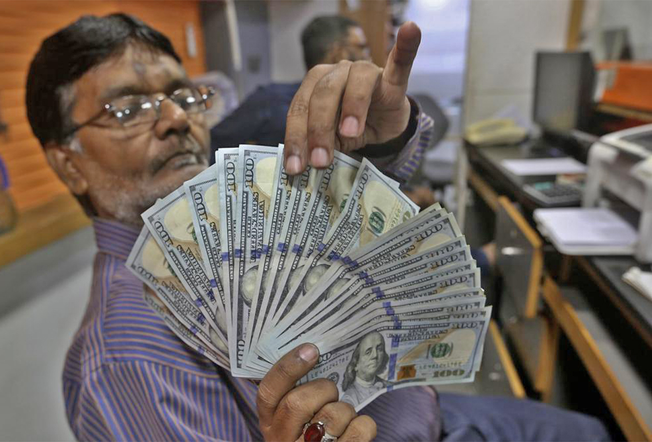 A Pakistani money trader checks U.S. 100 dollar notes at a currency exchange office, in Karachi, Pakistan, on May 19, 2022. (AP)