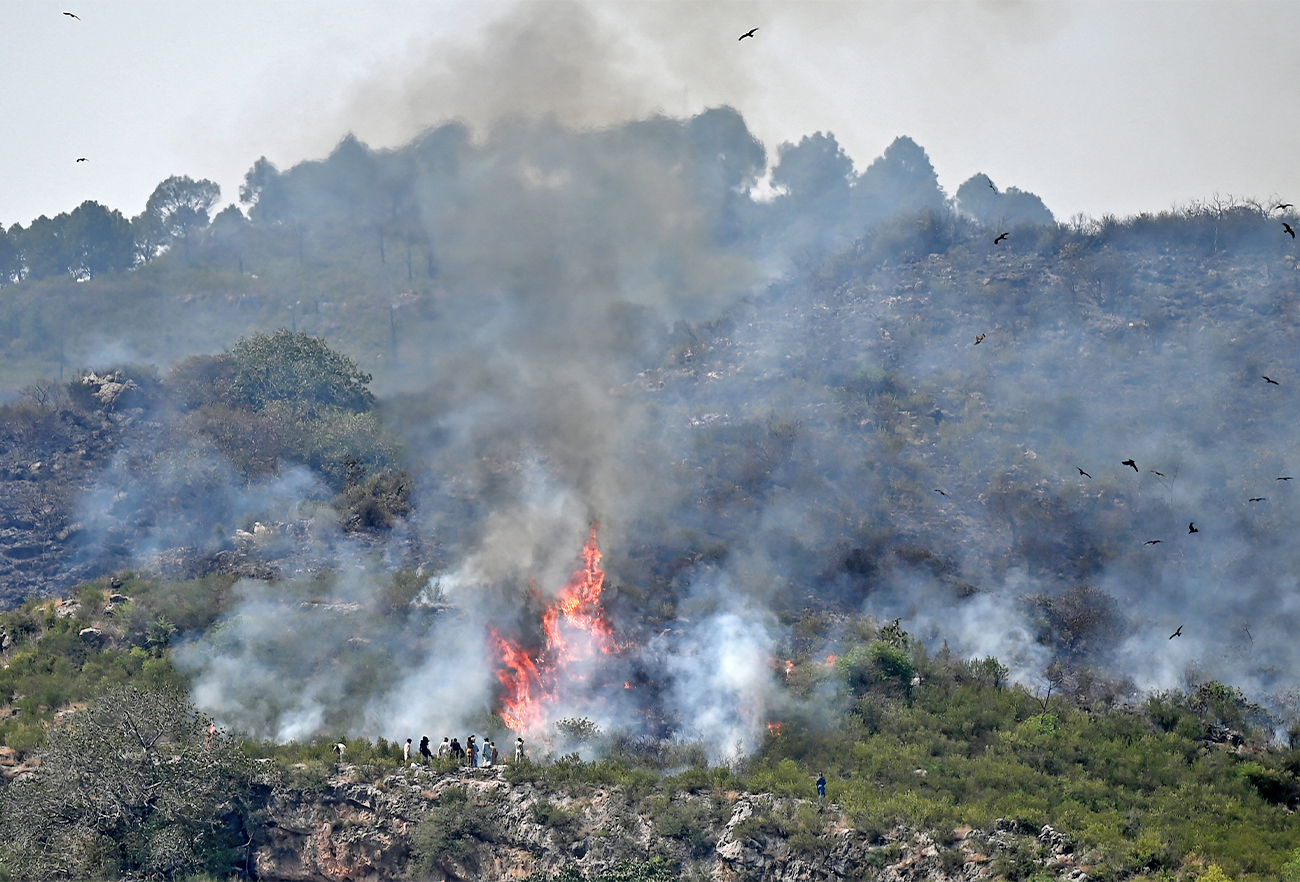 Capital Development Authority officials and Margalla rangers gather beside a fire, which erupted on Margalla Hills due to rising temperatures on a hot summer day near Saidpur village in Islamabad on May 28, 2021. (AFP/File)