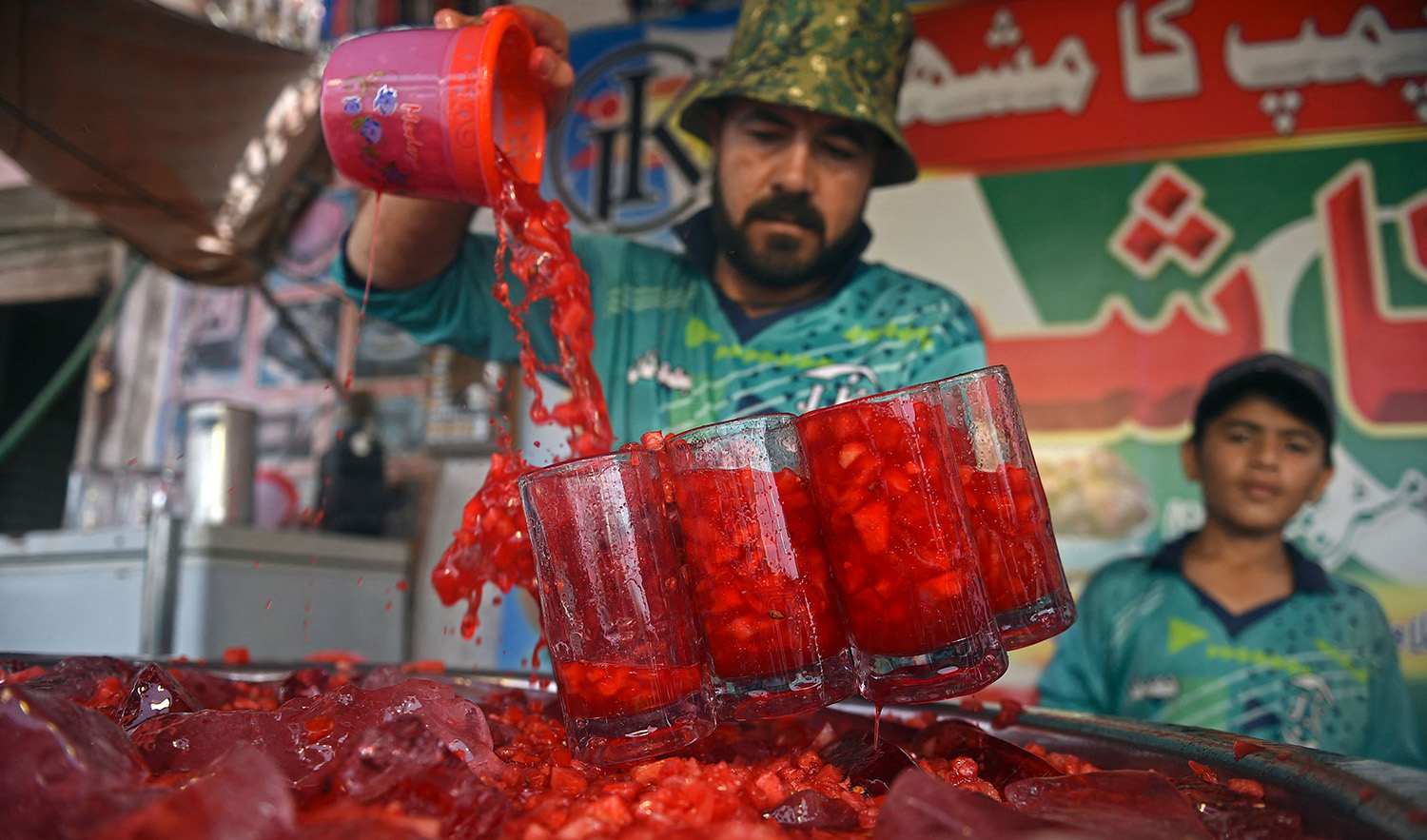 In this photograph taken on May 25, 2022, a vendor prepares to serve Rooh Afza watermelon beverages to customers along a roadside stall in Karachi. (AFP/File)