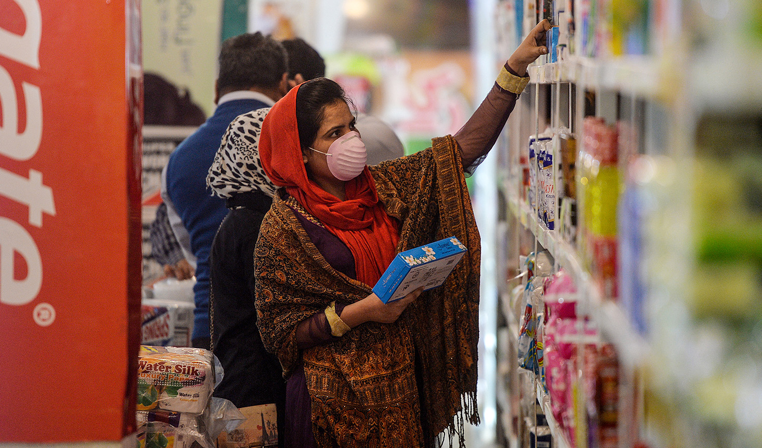 A woman wearing a facemask buys grocery items from a utility store in Islamabad, Pakistan, on March 17, 2020. (AFP/File)