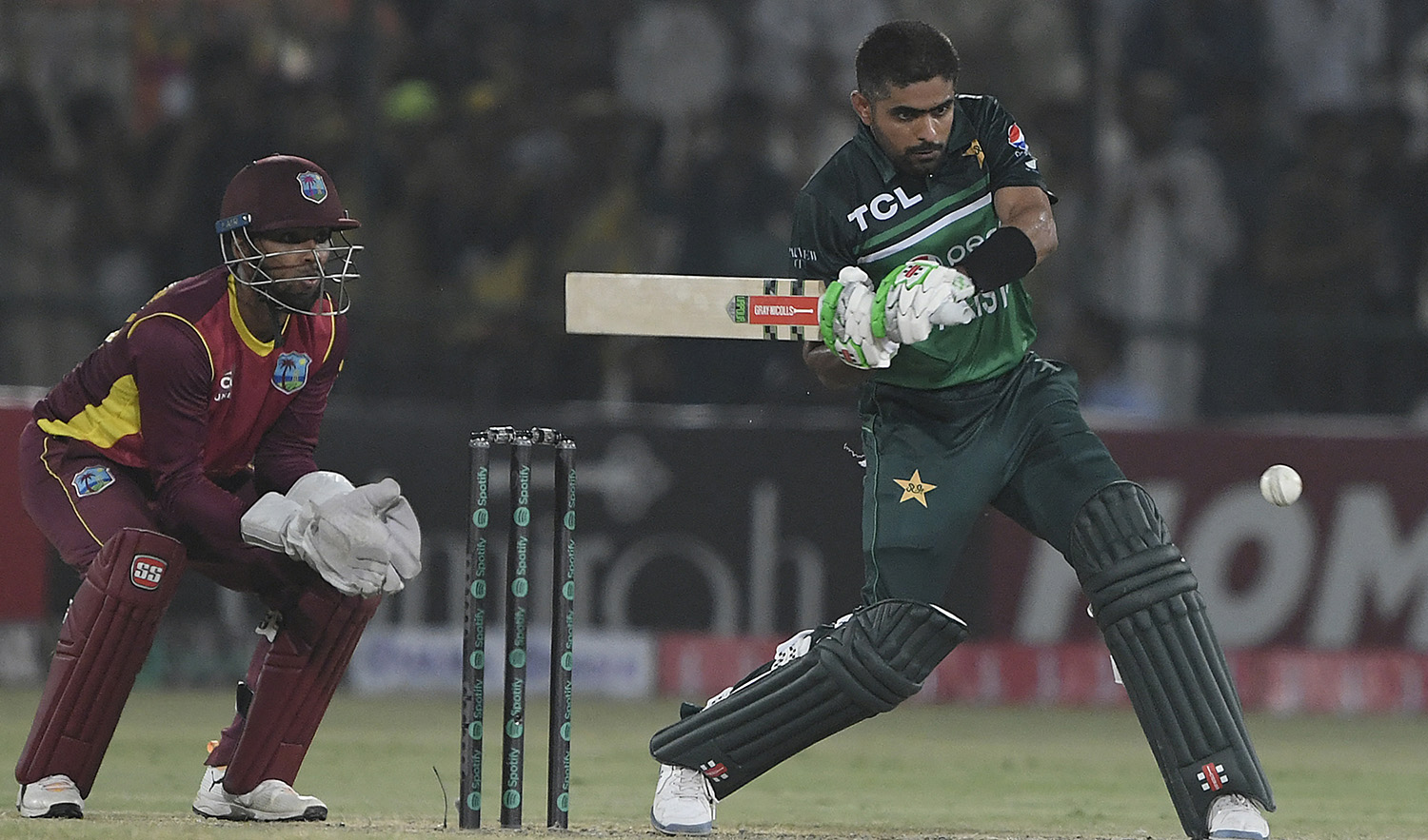 Pakistan's captain Babar Azam (R) plays a shot as West Indies’ captain wicketkeeper Nicholas Pooran watches during the first one-day international (ODI) cricket match at the Multan Cricket Stadium in Multan on June 8, 2022. (AFP)