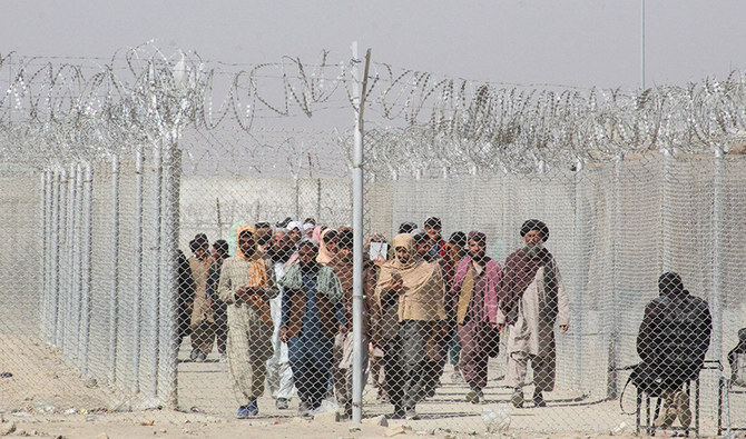 Pakistan's and Afghan's nationals walk along a fenced corridor as they enter Pakistan through the Pakistan-Afghanistan border crossing point in Chaman on February 27, 2022. (AFP)