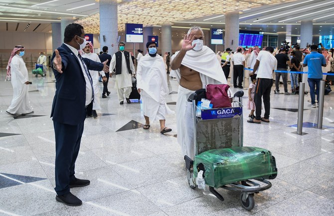 Mask-clad Pakistani travellers arriving to Saudi Arabia to perform the year-round Umrah pilgrimage, walk with their luggage at King Abdulaziz International Airport in the Red Sea coastal city of Jeddah on November 30, 2020. (AFP/ File)
