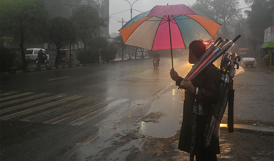 A street vendor carries umbrellas as he waits for customers along a road during a rain shower in Lahore on January 19, 2022. (AFP/FILE)