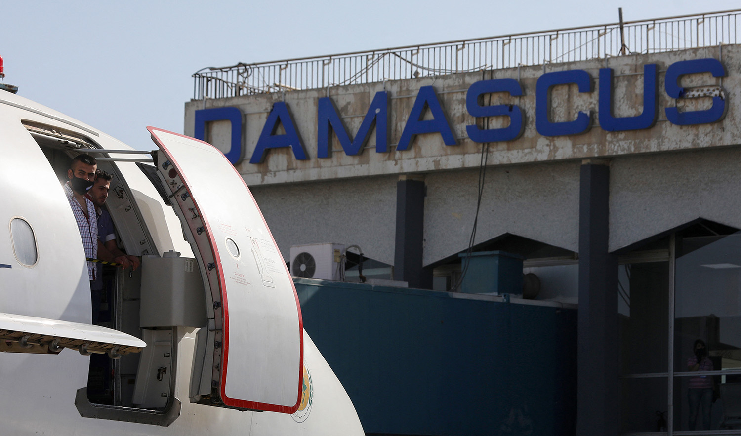 People stand on the door of a plane at the Damascus International Airport on the outskirts of Syria's capital on October 1, 2020. (AFP/File)