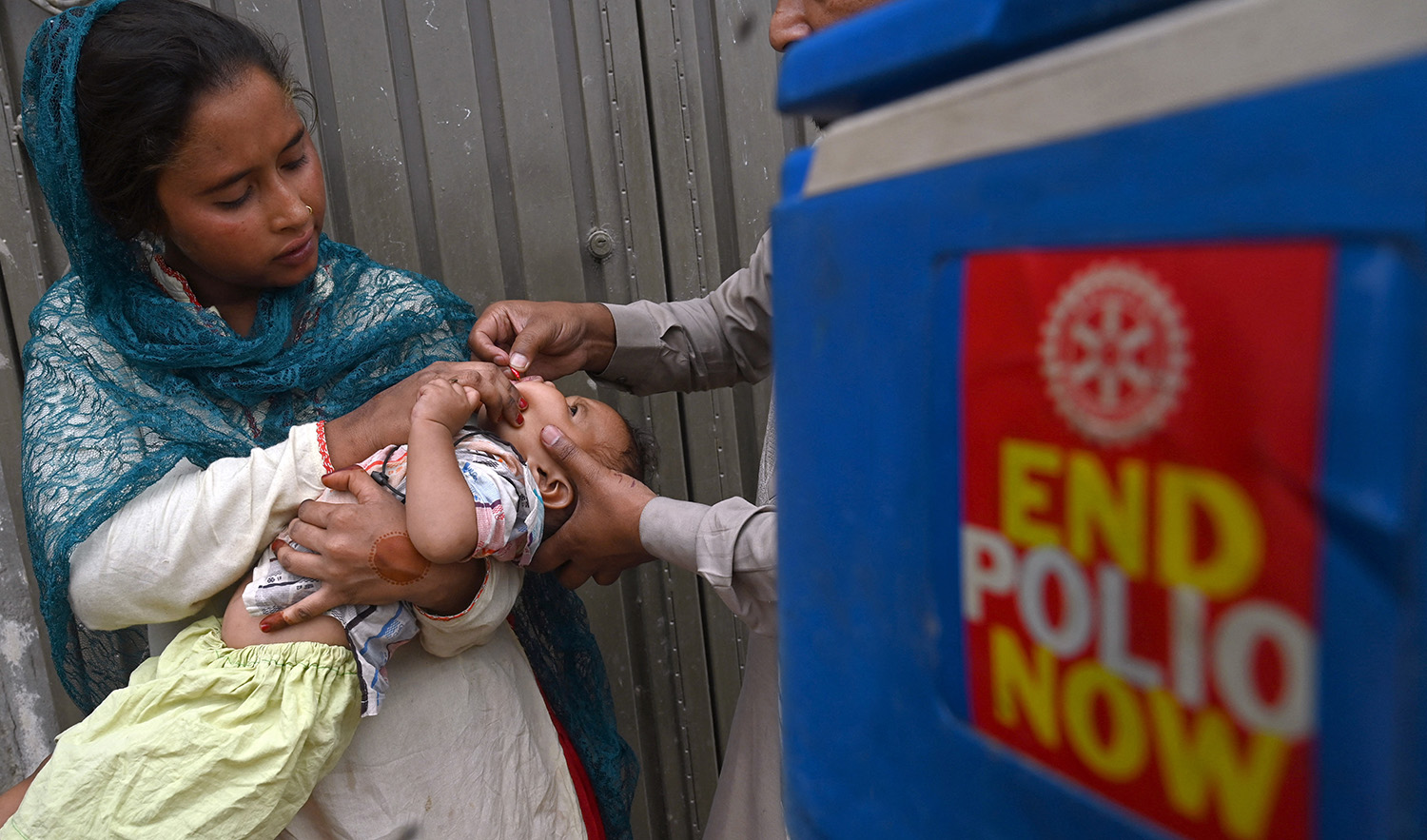A health worker administers polio vaccine drops to a child during a door-to-door polio vaccination campaign at a slum area in Lahore on May 23, 2022. (AFP/File)