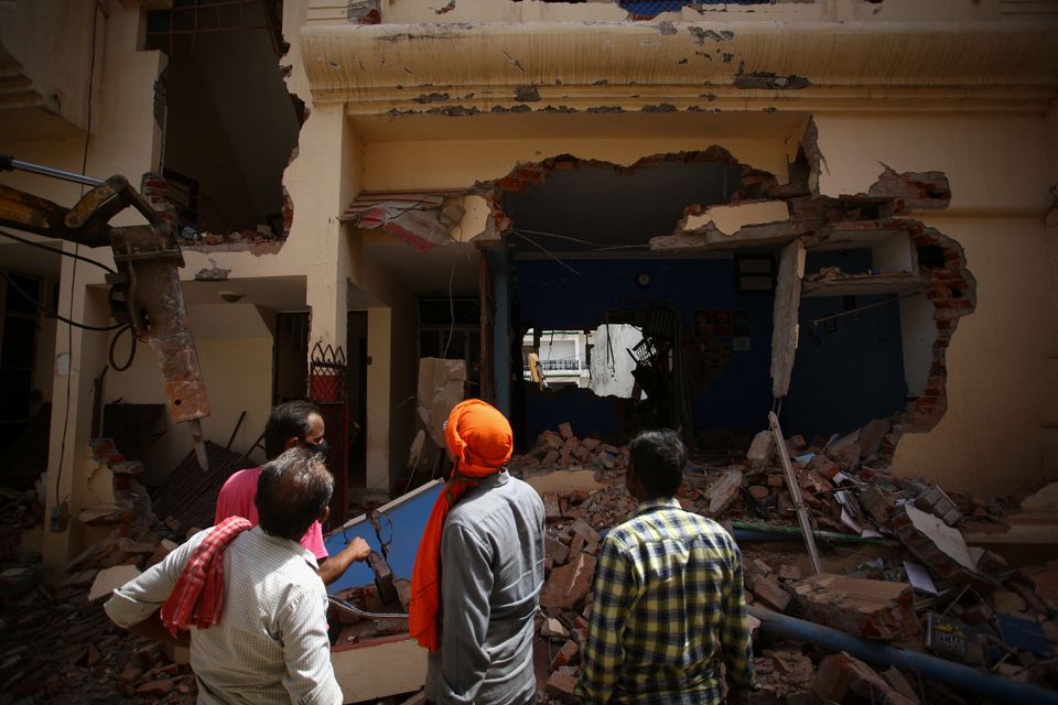 People watch as a bulldozer demolishes the house of a Muslim man in Prayagraj, India on June 12, 2022. (REUTERS)