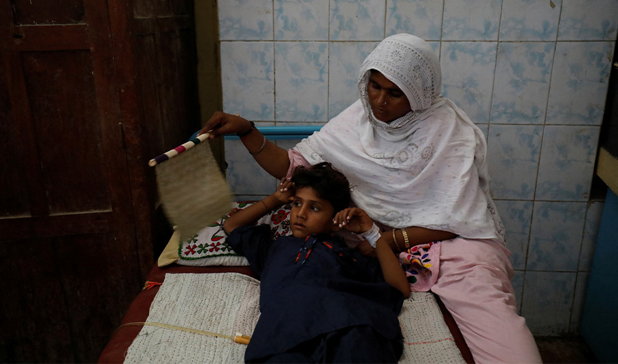 Rabia fans her son, Manish Kumar, 10, as he lies in bed after having a bladder stone removed, during a heatwave, at Civil Hospital, Jacobabad, Pakistan, May 15, 2022. (REUTERS)