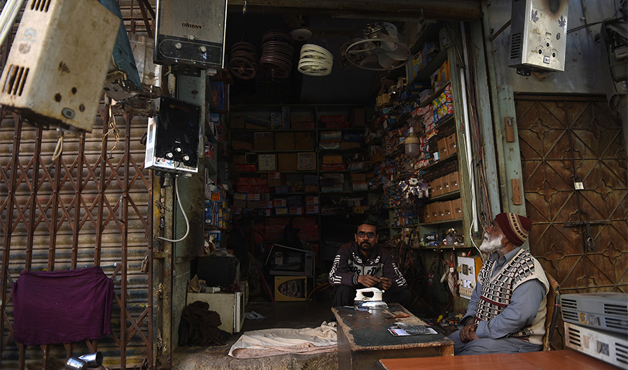 A shopkeeper sits inside his electronic repairing shop in Karachi on January 10, 2021, as the country hit by nationwide power blackout. (AFP/FILE)