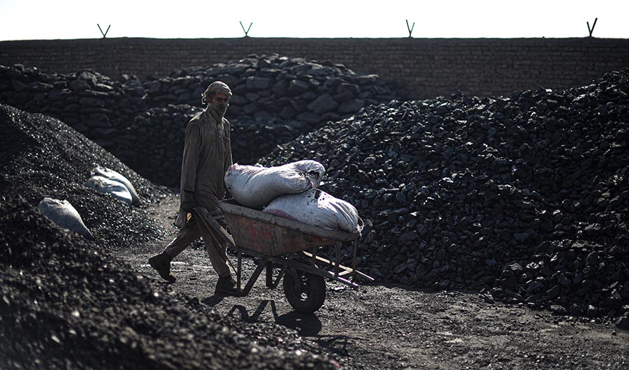 This photo taken on November 17, 2021 shows a day labourer pushing a wheelbarrow at a coal yard on the outskirts of Kabul. (AFP/FILE)