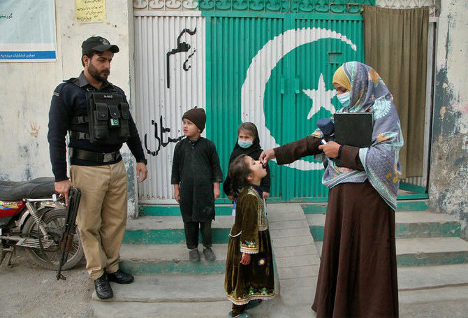 A police officer stands guard while a health worker administers a polio vaccine to a child, in Peshawar, Pakistan, on February 28, 2022. (AP/File)