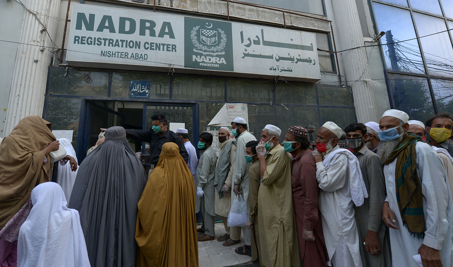 Residents wearing face masks line up in a queue outside the National Database and Registration Authority (NADRA) office in Peshawar, Pakistan, on May 4, 2020. (AFP/File)
