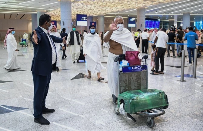 Mask-clad Pakistani travellers arriving to Saudi Arabia to perform the year-round Umrah pilgrimage, walk with their luggage at King Abdulaziz International Airport in the Red Sea coastal city of Jeddah on November 30, 2020. (AFP/ File)