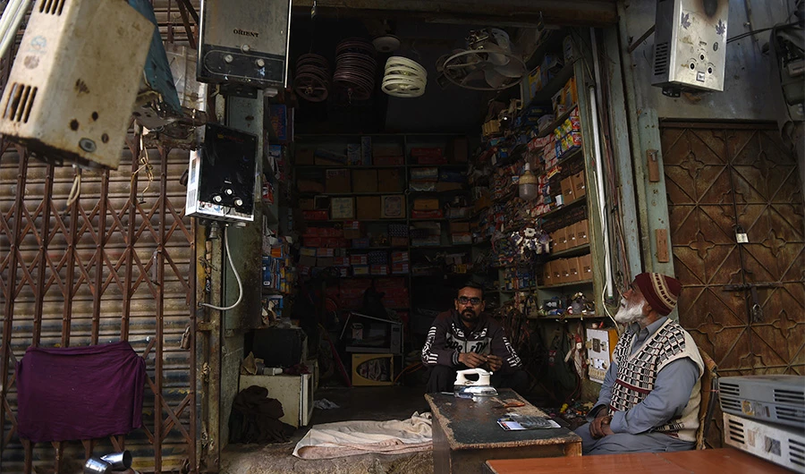 A shopkeeper sits inside his electronic repairing shop in Karachi on January 10, 2021, as the country hit by nationwide power blackout. (AFP/FILE)