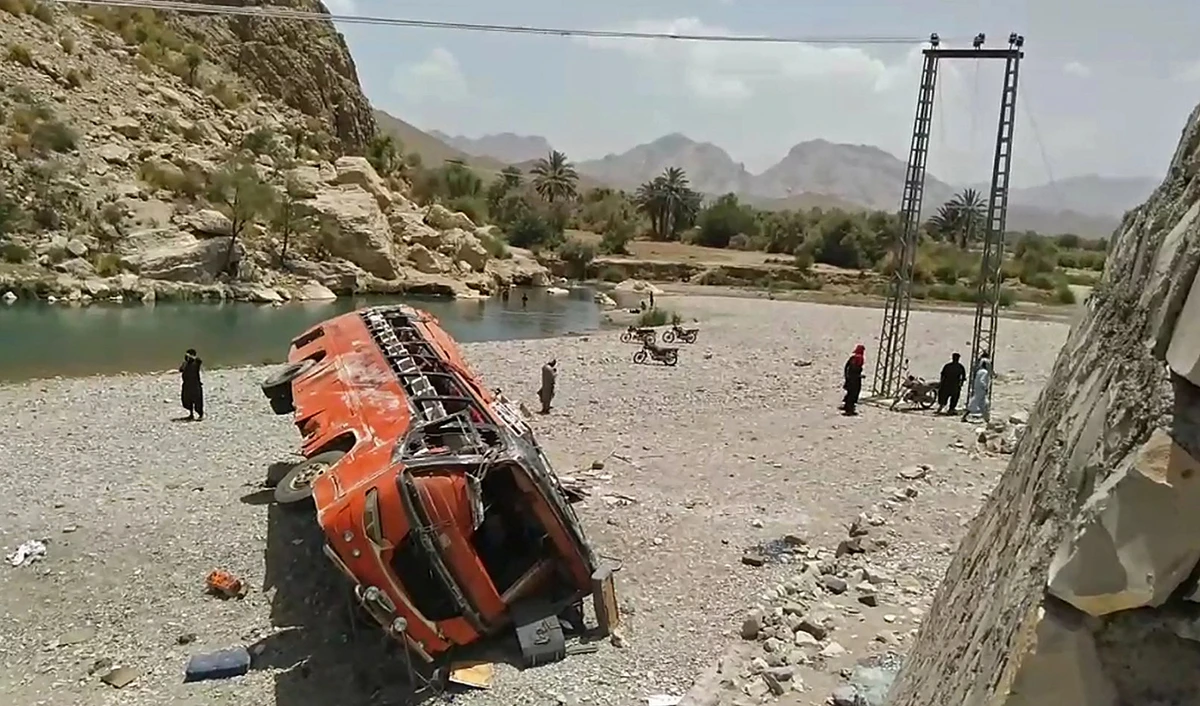 In this representational photo, onlookers stand next to a damaged bus at the site of an accident in a remote district of Balochistan province on June 11, 2021. (AFP/File)