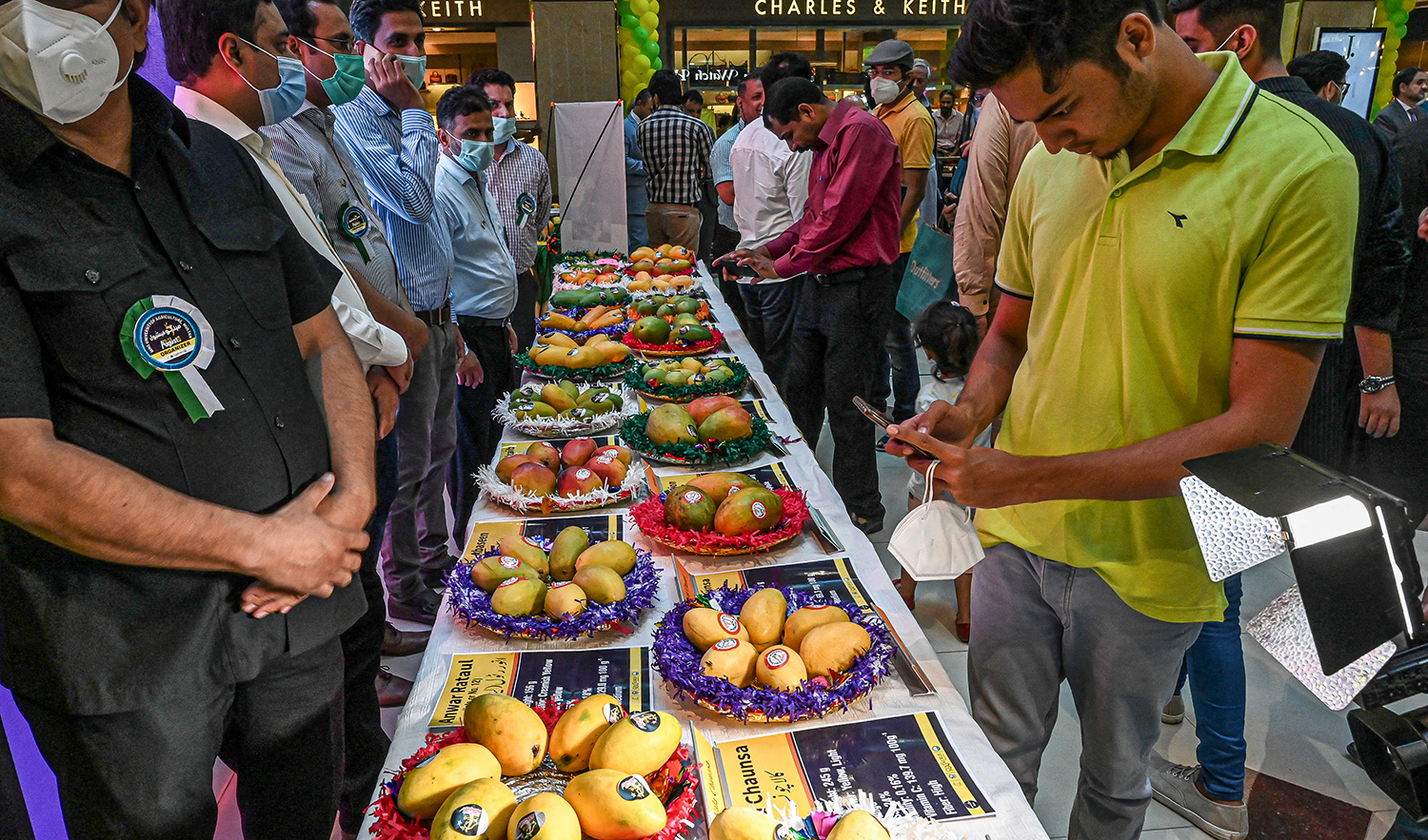 Exhibitors arrange different varieties of mangoes as visitors look around during the Mango Festival at Centaurus Mall in Islamabad on August 12, 2020. (AFP/File)
