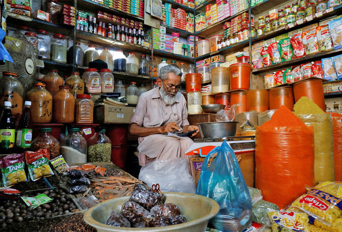 A shopkeeper uses a calculator while selling spices and grocery items along a shop in Karachi, Pakistan, on June 11, 2021. (REUTERS/File)