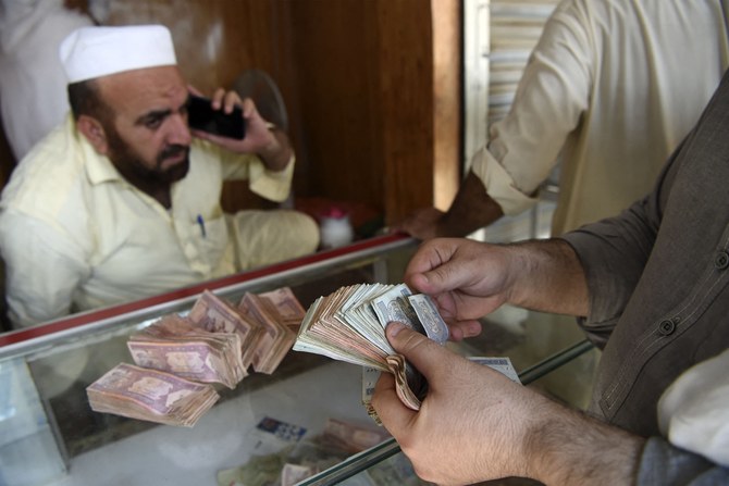 A money changer counts Afghanistan's banknotes Afghani in a market in Peshawar on September 7, 2021. (AFP)