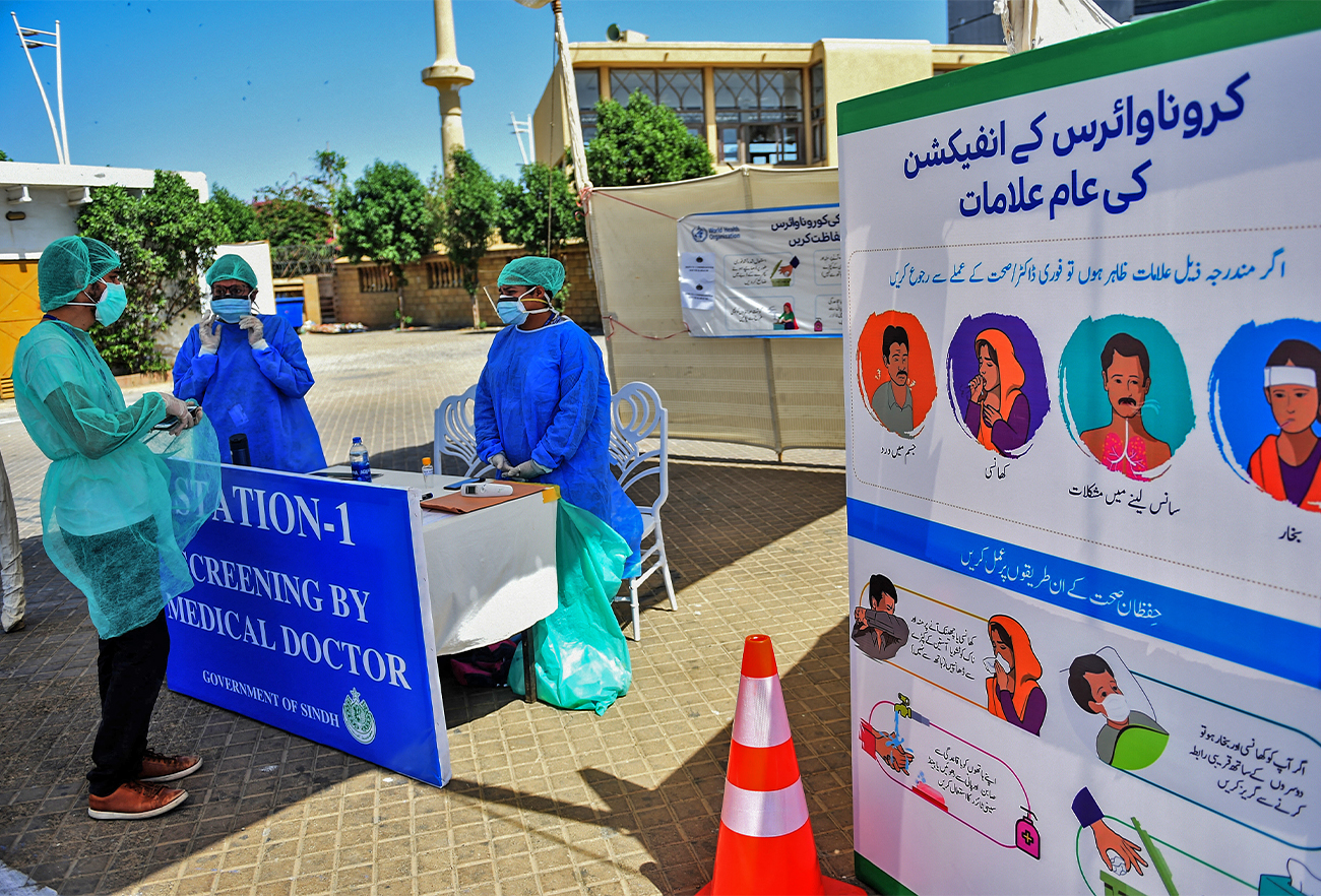 Medical staff members wearing protective gear gather around a desk at a drive-through testing facility point in Karachi, Pakistan, on April 4, 2020. (AFP/File)