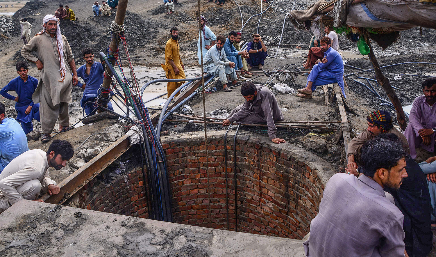 Miners and relatives gather outside the coal mine where at least 9 miners died after a flash flood following torrential rains inundated a coal mine, in Jhampir some 126 kilometers (100 miles) east of Karachi on July 7, 2022. (AFP/File)