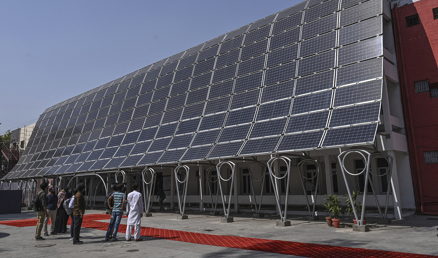 Students look at the facade of a building made with solar panels producing some 148 Kilowatts during its inauguration at the University of Engineering and Technology in Lahore on October 12, 2020. (AFP/File)